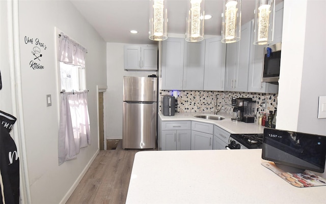 kitchen featuring sink, stainless steel appliances, hardwood / wood-style floors, pendant lighting, and decorative backsplash