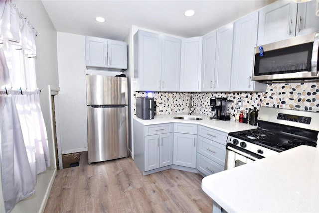 kitchen featuring sink, decorative backsplash, gray cabinets, appliances with stainless steel finishes, and light hardwood / wood-style floors