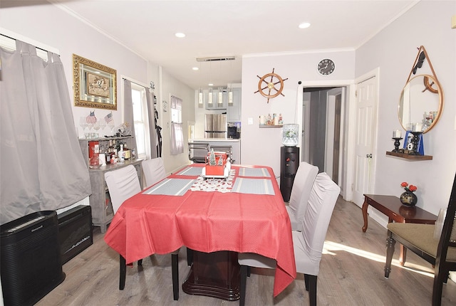 dining room with ornamental molding and light wood-type flooring