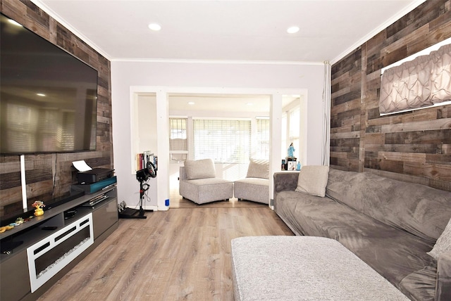 living room with light hardwood / wood-style floors, crown molding, and wood walls