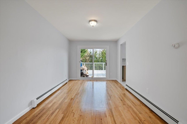 empty room featuring baseboard heating and light hardwood / wood-style floors