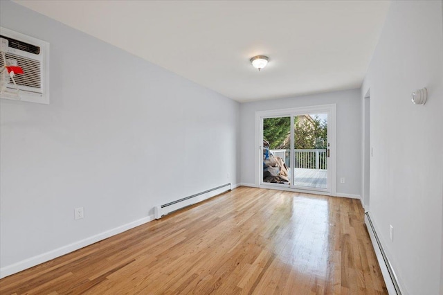 empty room featuring baseboard heating, light hardwood / wood-style flooring, and an AC wall unit