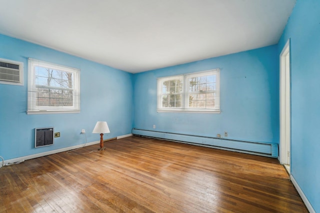 spare room featuring a wall mounted air conditioner, hardwood / wood-style floors, plenty of natural light, and a baseboard heating unit