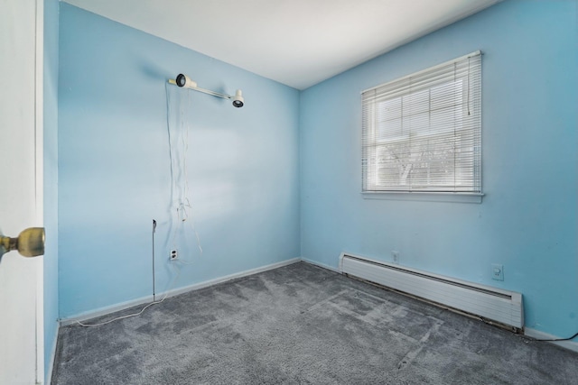 spare room featuring dark colored carpet and a baseboard heating unit