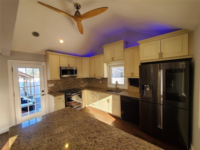 kitchen with stainless steel appliances, dark stone countertops, sink, backsplash, and vaulted ceiling