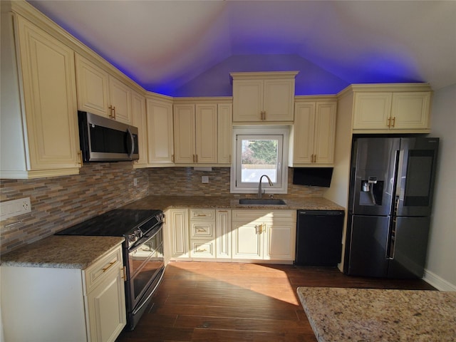 kitchen with lofted ceiling, black appliances, sink, light stone countertops, and cream cabinetry