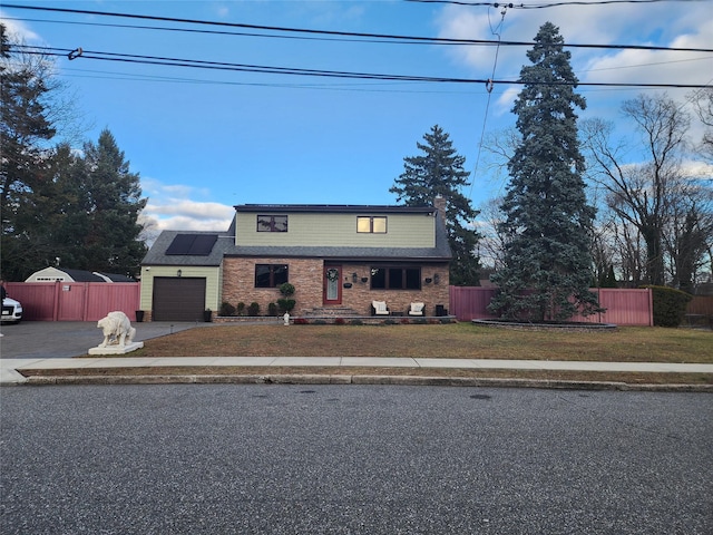 view of front property with a front lawn, a garage, and solar panels