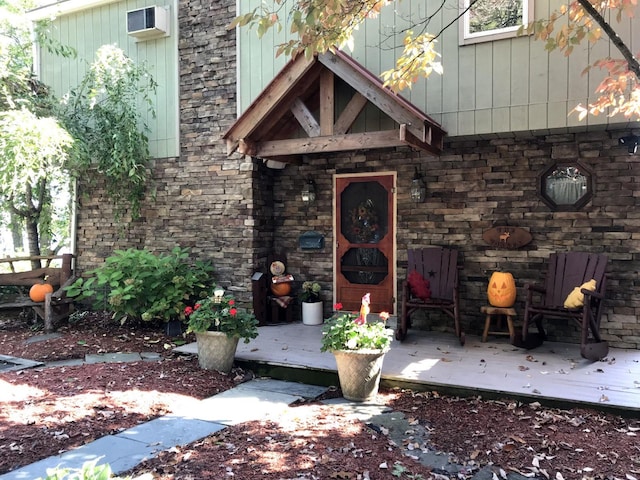 view of exterior entry with an AC wall unit and a wooden deck