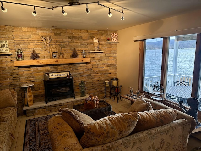 living room with a fireplace, a water view, light tile patterned flooring, and track lighting