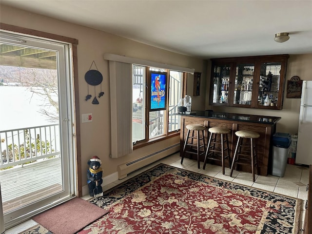 bar with light tile patterned flooring, a healthy amount of sunlight, and a baseboard heating unit