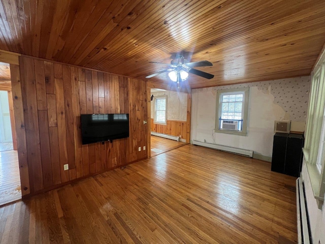 unfurnished living room featuring hardwood / wood-style floors, wooden walls, and a baseboard heating unit