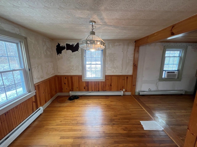 unfurnished dining area with hardwood / wood-style floors, a chandelier, and a baseboard radiator