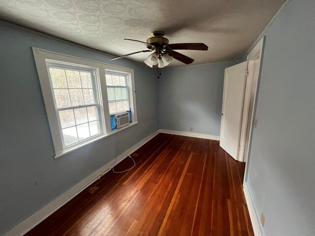 spare room with ceiling fan, cooling unit, and dark wood-type flooring