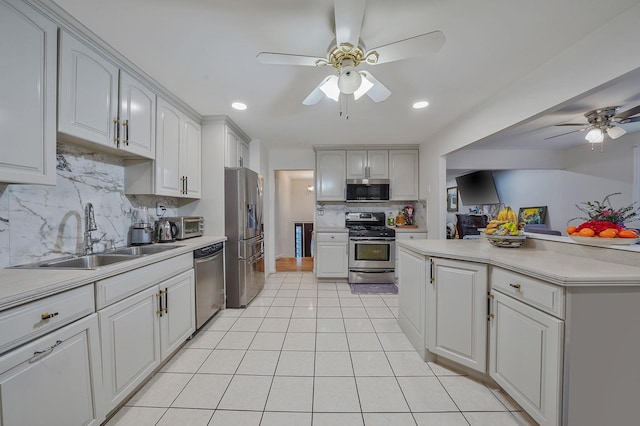 kitchen with sink, tasteful backsplash, light tile patterned floors, appliances with stainless steel finishes, and ceiling fan