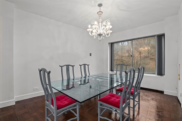 dining space featuring dark parquet flooring and a notable chandelier