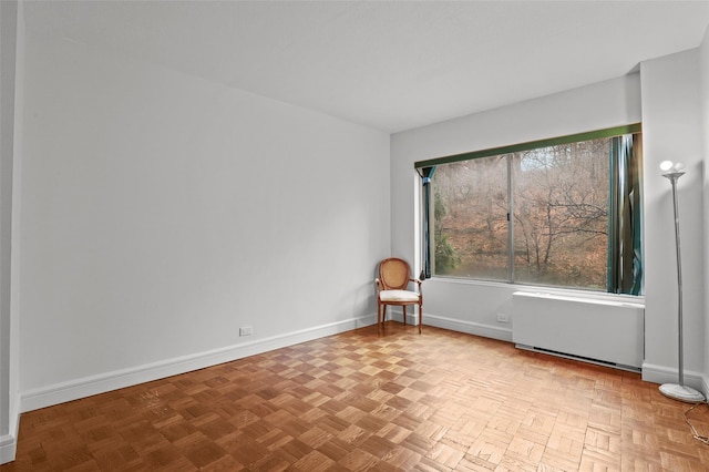 empty room with light parquet flooring and radiator heating unit