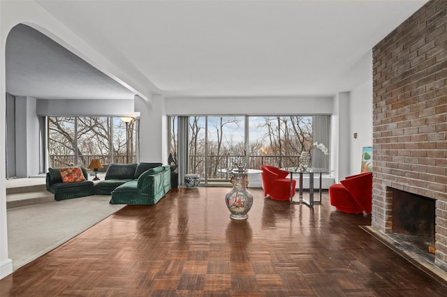 living room with a brick fireplace and dark parquet floors