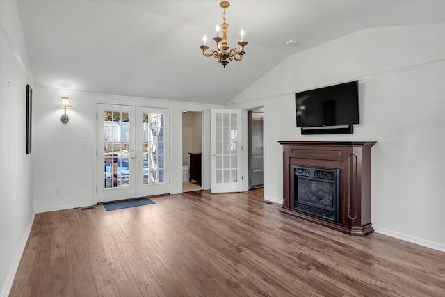 unfurnished living room featuring french doors, an inviting chandelier, vaulted ceiling, and hardwood / wood-style flooring