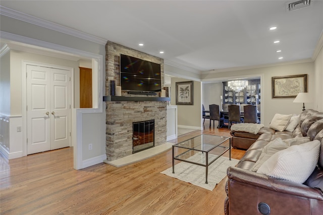 living room with a fireplace, an inviting chandelier, ornamental molding, and light hardwood / wood-style flooring