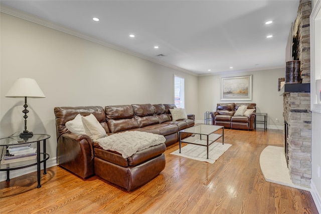 living room with light hardwood / wood-style flooring, a stone fireplace, and crown molding