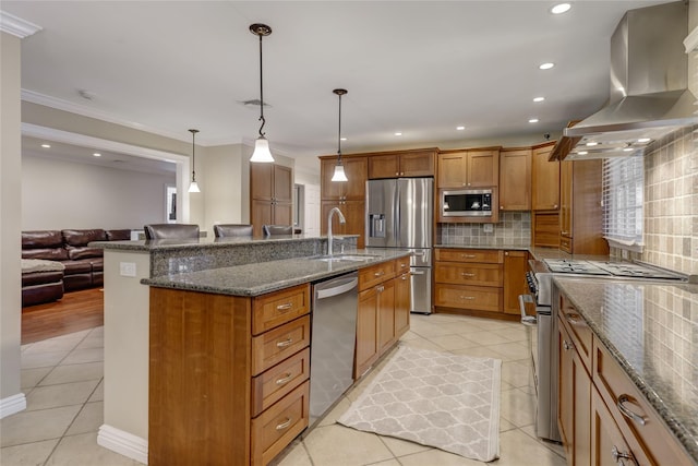 kitchen with island range hood, decorative light fixtures, a large island with sink, appliances with stainless steel finishes, and sink