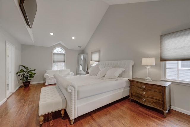 bedroom with vaulted ceiling, multiple windows, and hardwood / wood-style flooring