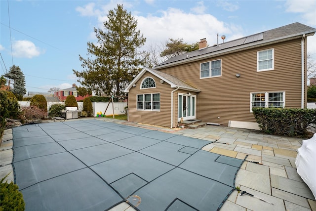 rear view of property with solar panels and a patio