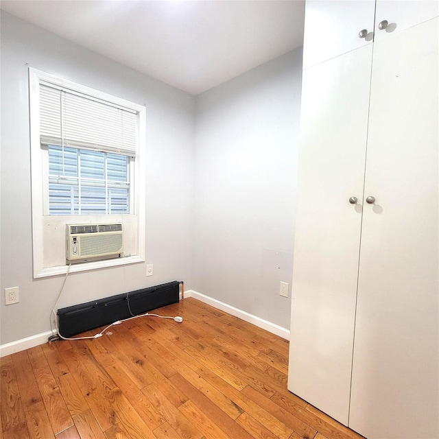 empty room with cooling unit, light wood-type flooring, and baseboard heating