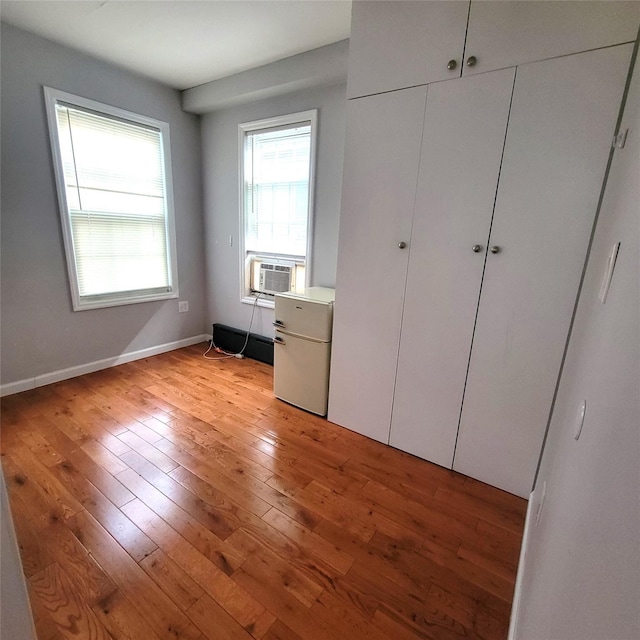 unfurnished bedroom with cooling unit and light hardwood / wood-style floors