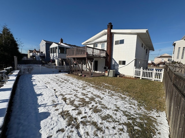 snow covered house with central AC unit and a wooden deck