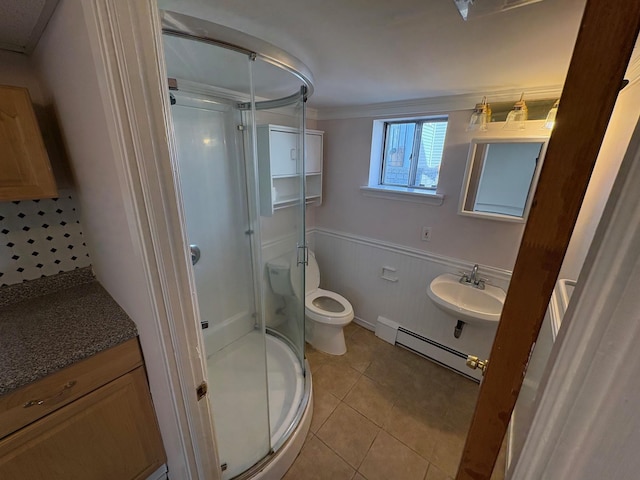 bathroom featuring baseboard heating, crown molding, sink, toilet, and a shower with shower door