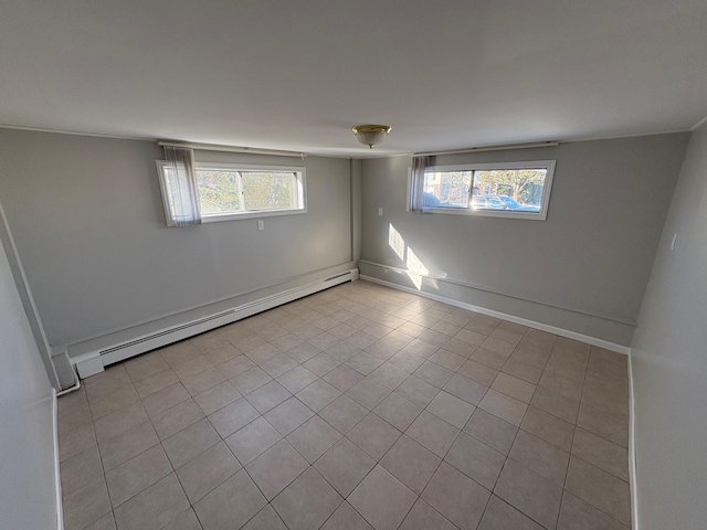 tiled empty room featuring plenty of natural light and a baseboard radiator