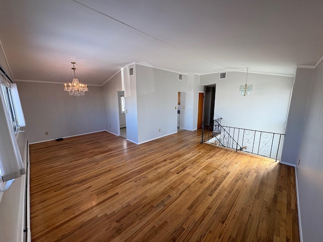 empty room with hardwood / wood-style floors, an inviting chandelier, baseboard heating, and ornamental molding