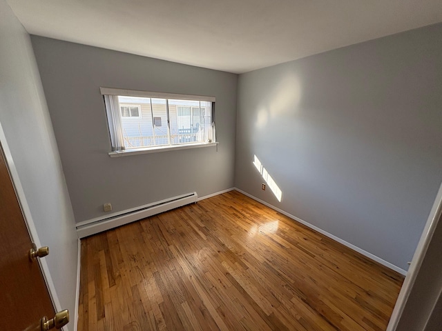 spare room with baseboard heating and wood-type flooring