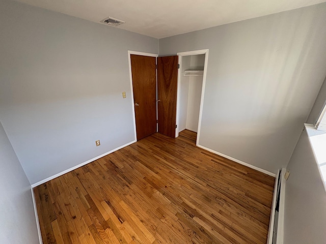 unfurnished bedroom with hardwood / wood-style flooring and a closet