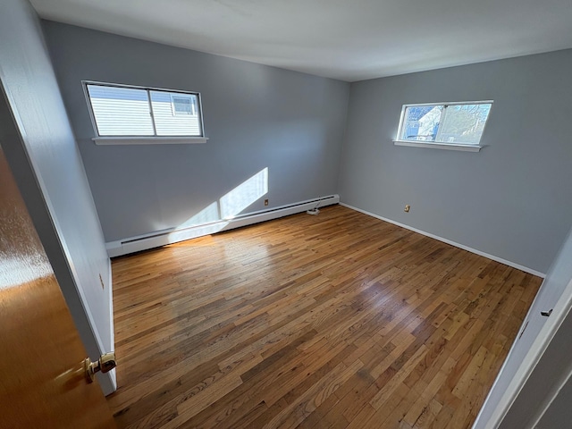 unfurnished room featuring baseboard heating and hardwood / wood-style flooring