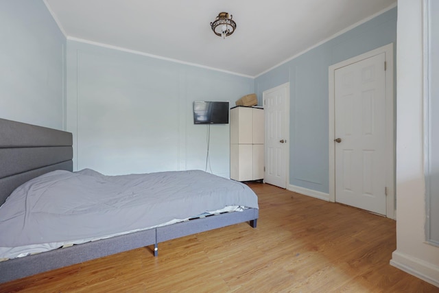 bedroom with crown molding and light hardwood / wood-style floors