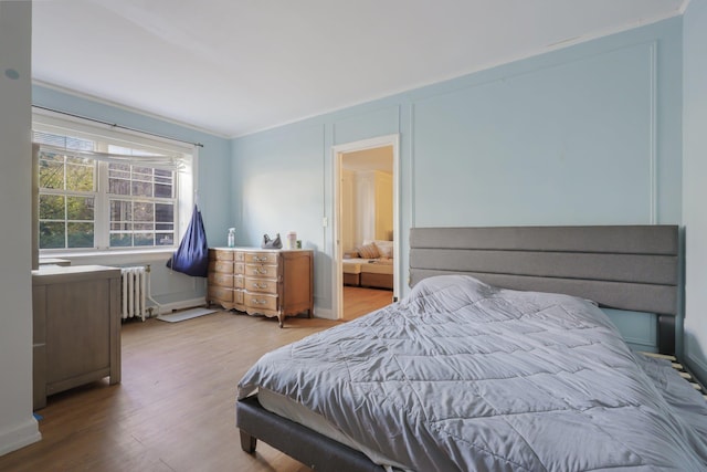 bedroom with hardwood / wood-style flooring, radiator heating unit, and ornamental molding