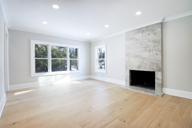 unfurnished living room with crown molding, a high end fireplace, and light wood-type flooring