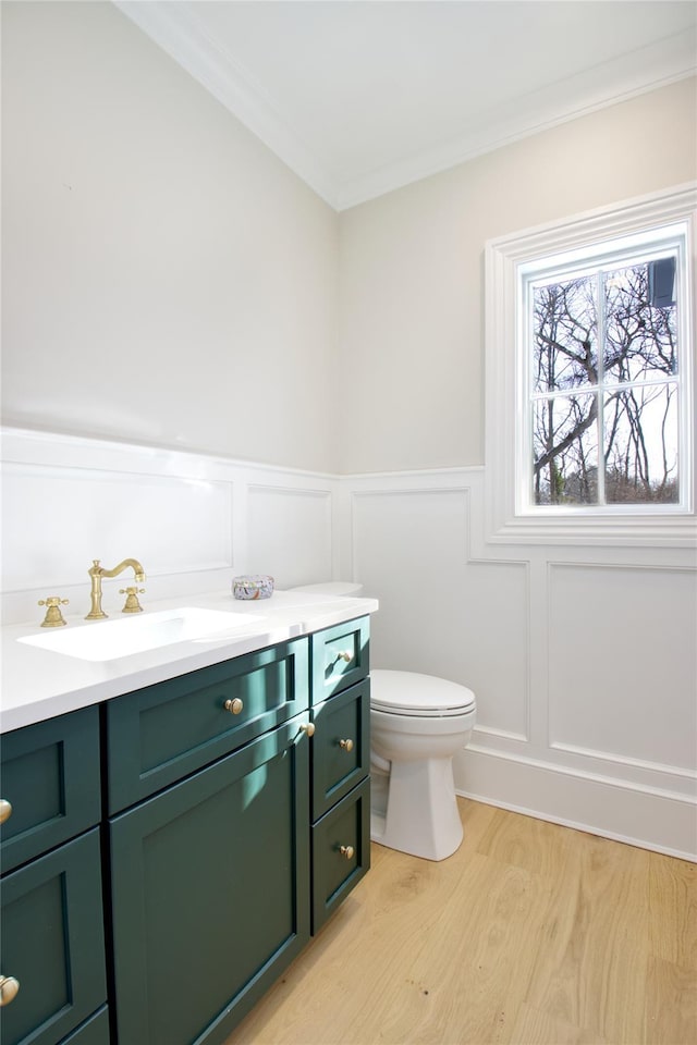 bathroom with ornamental molding, vanity, toilet, and wood-type flooring