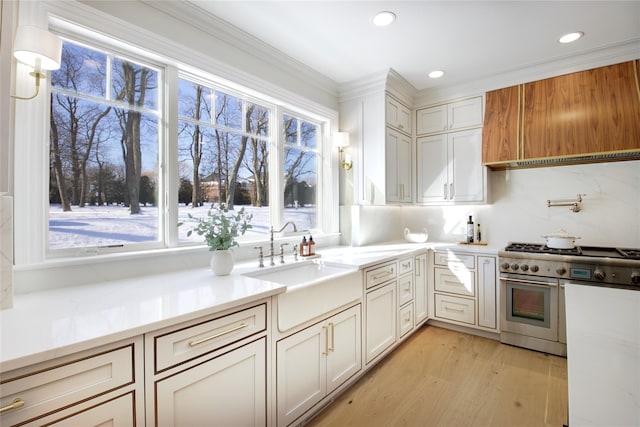 kitchen with sink, light wood-type flooring, custom range hood, range with two ovens, and white cabinets