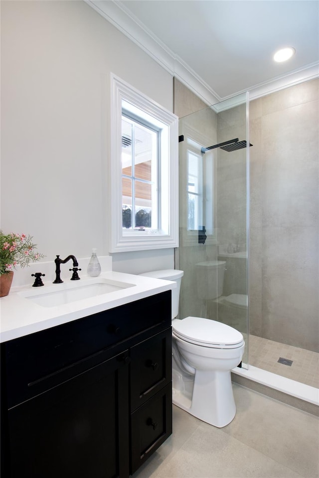 bathroom with tile patterned floors, toilet, a tile shower, ornamental molding, and vanity