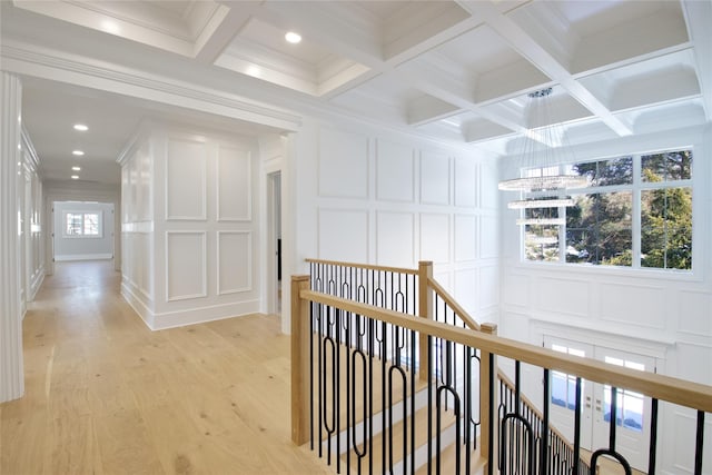 corridor with coffered ceiling, ornamental molding, light hardwood / wood-style floors, and beamed ceiling