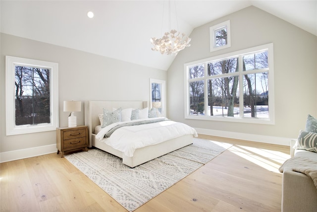 bedroom featuring vaulted ceiling, hardwood / wood-style floors, and a notable chandelier