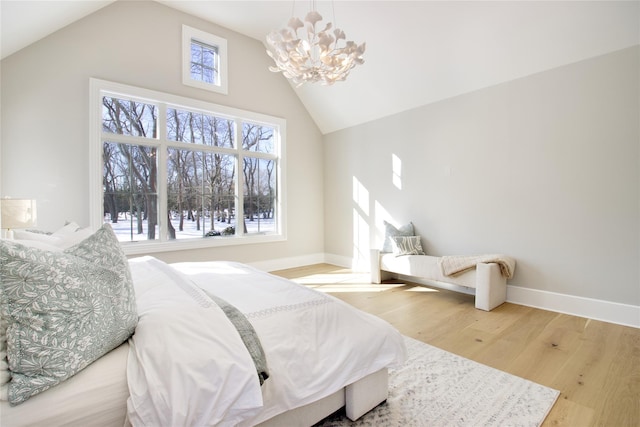 bedroom with an inviting chandelier, wood-type flooring, and high vaulted ceiling