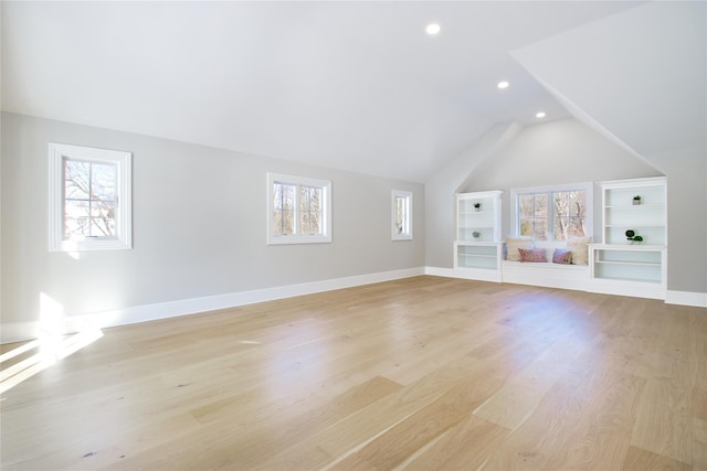 additional living space with a healthy amount of sunlight, vaulted ceiling, and light hardwood / wood-style flooring