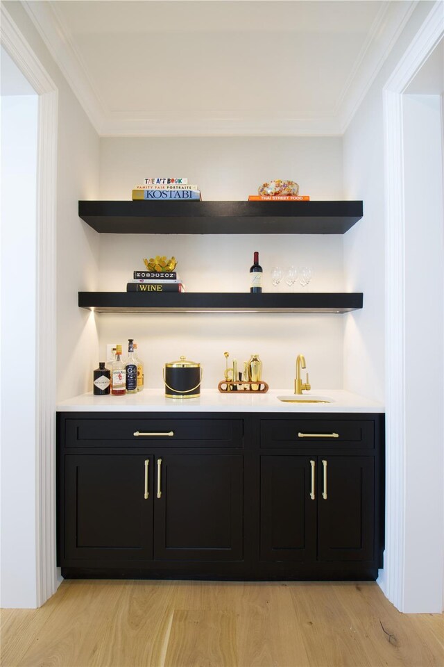 bar featuring ornamental molding, light hardwood / wood-style floors, and sink