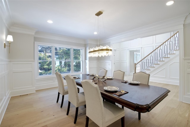 dining area with a notable chandelier, crown molding, and light wood-type flooring