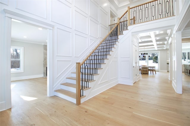 staircase featuring coffered ceiling, crown molding, wood-type flooring, and beam ceiling