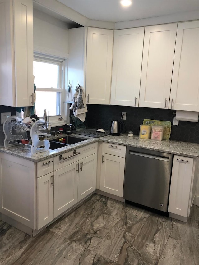 kitchen with backsplash, white cabinets, light stone counters, sink, and dishwasher